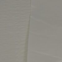 Close-up photo of a nonwoven polyethylene laminate material to show texture. This polyethylene laminate sample is white.